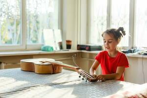 pequeño niña participación un roto guitarra, guitarra reparar foto