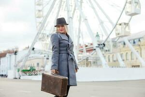 Young woman wearing hat walking outdoors on the city street near ferris wheel smiling cheerful. photo