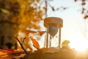 Autumn time theme, Sandglass on fallen leaves in various colors with copy space. photo