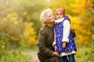 Grandmother and her granddaughter picking berries in the forest photo