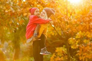 portrait of a young woman and her daughter in the autumn park photo