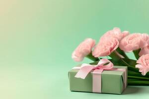 Top view of pink present boxes with ribbon, carnation flowers on a soft pastel green background with copy space, photo