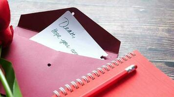 a red rose and a note are placed on a wooden table video