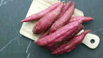 a wooden cutting board with a bunch of purple sweet potatoes video