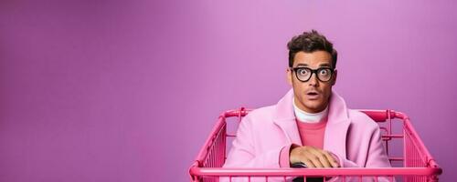 Portrait of a young latino man in glasses with a shopping cart on a pink background with empty space for text photo