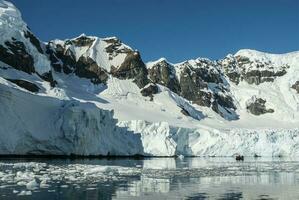 Tourists watching glaciers and mountains in Paradise bay, Antarctic peninsula, Antartica.. photo