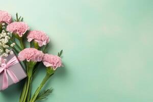 Top view of pink present boxes with ribbon, carnation flowers on a soft pastel green background with copy space, photo