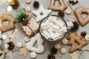 un taza de cacao con Malvaviscos y nuevo años pan de jengibre y un regalo en el mesa, bokeh luces en el primer plano. el concepto de postres y bebidas durante el Navidad vacaciones. foto