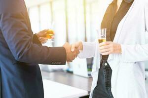 Business people hands shaking hands meeting join together and drinking white wine in office party photo