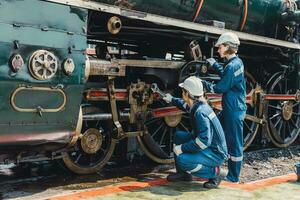 tren ingeniero equipo trabajando Servicio mantenimiento antiguo sucio Clásico clásico vapor motor locomotora en tren reparar taller a tren estación. foto