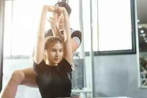 sano personas asiático joven mujer deporte ejercicio en aptitud gimnasio deporte club con personal entrenador instructores ayuda apoyo. foto