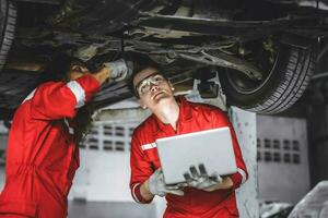 Mechanic male team staff worker working together under car auto service check tuning in garage photo