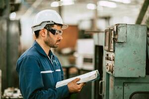 nuevo ingeniero trabajador leyendo usuario manual máquina instrucción guía libro a trabajando funcionar resolviendo problema en metal fábrica. foto