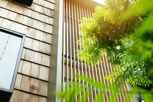 Modern home with wooden wall wooden slats and green tree for cooling sunshade and saving energy house exterior photo