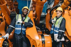 Happy portrait engineer worker robot arm welding assembly line maintenance service team in automation factory industry. photo