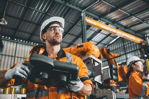 Engineer team working with robot welding in automation factory. People worker in safety suit control robotic arm in automated manufacturing industry technology. photo