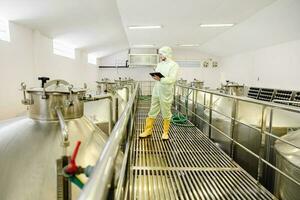 cervecería bebida fábrica trabajador trabajando cheque fermentación tanque con limpiar y higiene cubrir traje. foto