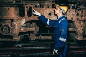 Train engineer team working service maintenance old dirty vintage classic steam engine locomotive in train repair workshop at train station. photo