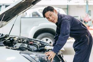 asiático masculino mecánico garaje personal trabajador coche motor Servicio en auto tienda contento sonriente retrato foto