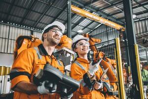 Engineer team working with robot welding in automation factory. People worker in safety suit control robotic arm in automated manufacturing industry technology. photo