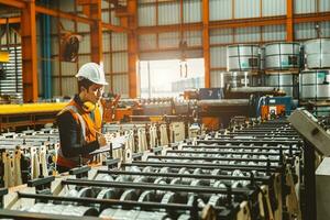 Young male engineer supervisor working QC in metal sheet manufactory work checking production line. photo