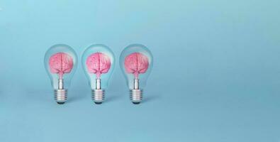 Brain on light bulb illuminated standing out from the crowd on blue background. photo