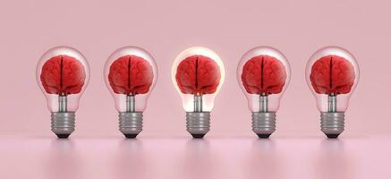 Brain inside a light bulb illuminated standing out from the crowd on pink background. Concept of inspiration. photo
