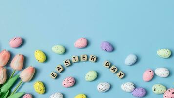 easter day concept with colorful easter eggs and tulips on blue background photo
