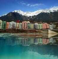 Beautiful colorful buildings reflected in the water with snowy mountains in the background in Innsbruck.. photo