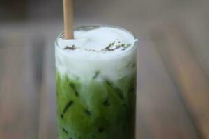 Iced matcha green tea latte in glass on wooden table photo