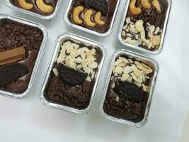 Chocolate cake brownie candies with nuts and chocolate chips in foil boxes. photo