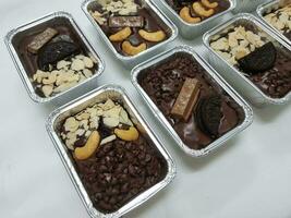 Chocolate cake brownie candies with nuts and chocolate chips in foil boxes. photo