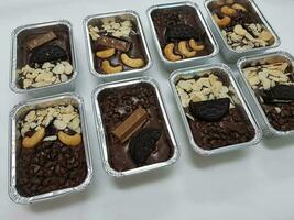 Chocolate cake brownie candies with nuts and chocolate chips in foil boxes. photo