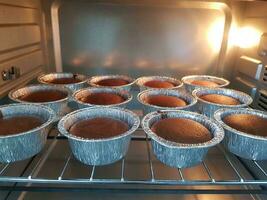 Chocolate muffins in a baking tray in the oven at night photo