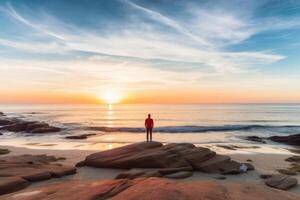 Man standing alone on the beach during sunset. photo