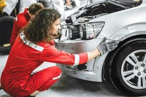 Mechanic garage auto workshop team working service repair fix damaged front bumper accident car photo
