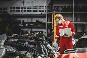 Old used car part warehouse worker checking inventory in garage. Staff worker working in recycle motor junkyard auto parts management. photo