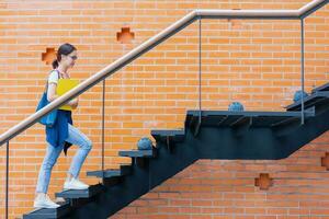 Universidad estudiante caminar escalada escalera paso arriba en colegio instalaciones a subir mayor éxito inteligente mujer concepto. foto