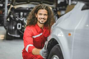 Hispanic male staff worker work in auto workshop happy smiling enjoy working servicing car tire replace photo