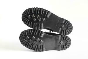 Lug soles of black combat boots on high heel platform lying on isolated white background photo