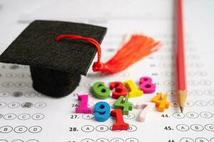 Graduation gap hat and pencil on answer sheet background  Education study testing learning teach concept. photo