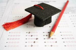 Graduation gap hat and pencil on answer sheet background, Education study testing learning teach concept. photo