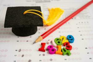 Graduation gap hat and pencil on answer sheet paper, Education study testing learning teach concept. photo