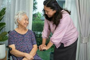 Caregiver help Asian senior woman on wheelchair with love at home. photo