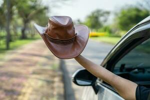 contento disfrutar y libertad en de viaje viaje con elevado mano y participación sombrero fuera de de ventana coche en verano vacaciones día festivo. foto