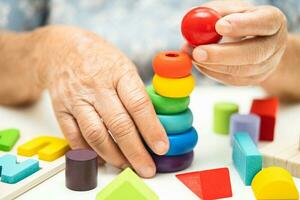 Alzheimer disease AD, Asian elderly woman patient suffering from dementia learn practical motor skills rehabilitation. photo