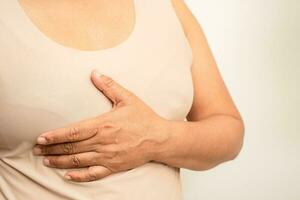 Asian woman patient checking and worry her breast, Breast Self Exam or BES, symbol of World Breast Cancer Day. photo