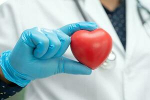 Doctor holding a red heart in hospital ward, healthy strong medical concept. photo