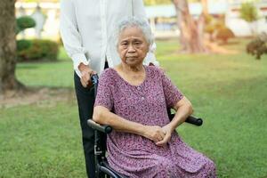 Caregiver help and care Asian elderly woman use walker with strong health while walking at park in happy fresh holiday. photo