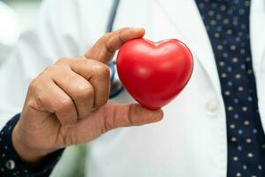 médico sosteniendo un corazón rojo en la sala del hospital, concepto médico fuerte y saludable. foto